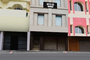 Hotel con insegna che indica servizio aziendale, caratterizzato da una facciata moderna con numerose finestre e una persiana abbassata a destra.