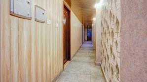 A hallway with wooden paneling, a tiled floor, and a patterned wall. - Deluxehotel Riash (Prayagraj)