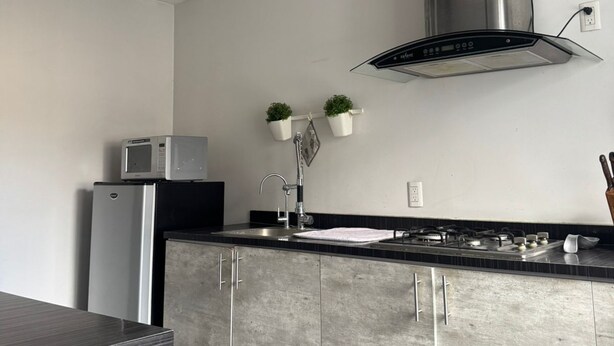 A modern kitchen with a built-in microwave, stainless steel appliances, a ceiling fan, and a gas stove. - COZY ROOM IN PROVIDENCIA PUNTO SAO PAULO (Guadalajara)