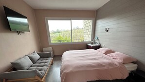 A bedroom with a bed, a sofa, a TV, a window, and a nightstand. - Architect's house in the countryside (Sainte-Geneviève-lès-Gasny)