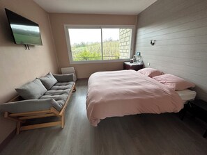 A bedroom with a bed, a sofa, a TV, a window, and a nightstand. - Architect's house in the countryside (Sainte-Geneviève-lès-Gasny)