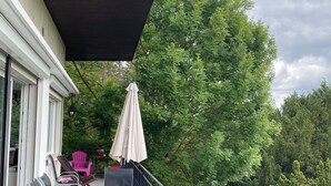 A balcony with outdoor furniture, a table, and chairs, surrounded by greenery and trees. - Architect's house in the countryside (Sainte-Geneviève-lès-Gasny)