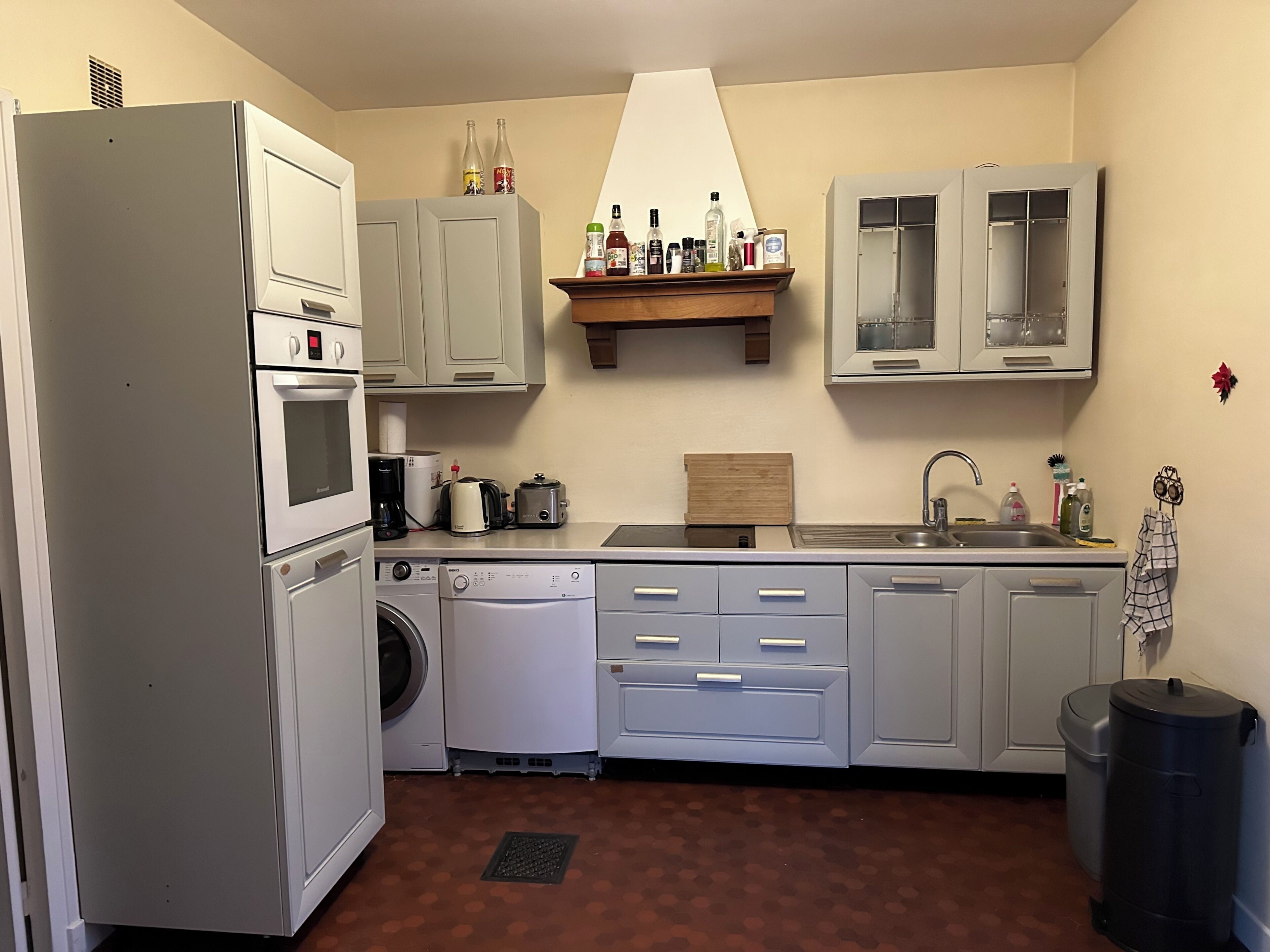 Cocina compacta con refrigerador, horno, lavadora y pileta.