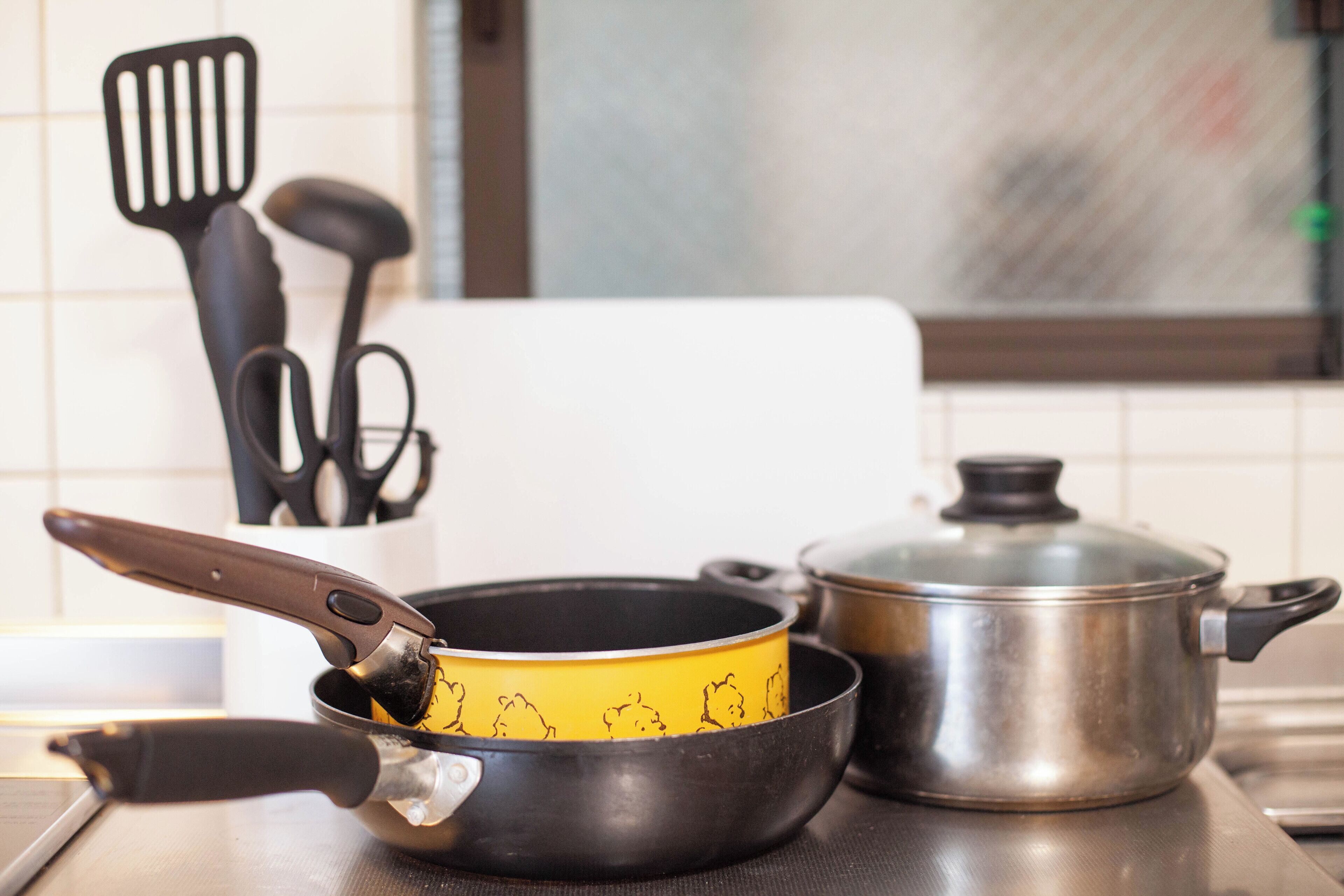 Een keuken met een koekenpan, een pan en een spatel op het aanrecht.