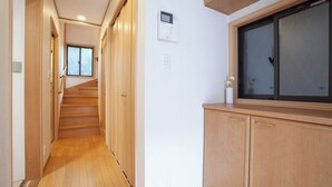 A hallway with wooden flooring, a window, and a wall-mounted thermostat. - Lucky Higashi Mizue (Tokyo)