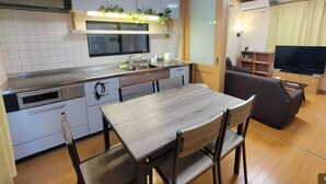 A compact kitchen with a dining area, a TV, and a sofa. - Lucky Higashi Mizue (Tokyo)