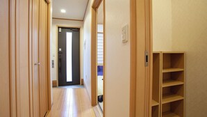 A hallway with wooden doors, a tiled floor, and a built-in shelf unit. - Lucky Higashi Mizue (Tokyo)