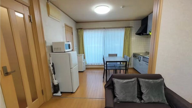 A compact living space with a kitchenette, a dining area, and a sofa. - Lucky Higashi Mizue (Tokyo)