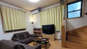 A living room with a sofa, a coffee table, a TV, a bookshelf, and a staircase. - Lucky Higashi Mizue (Tokyo)