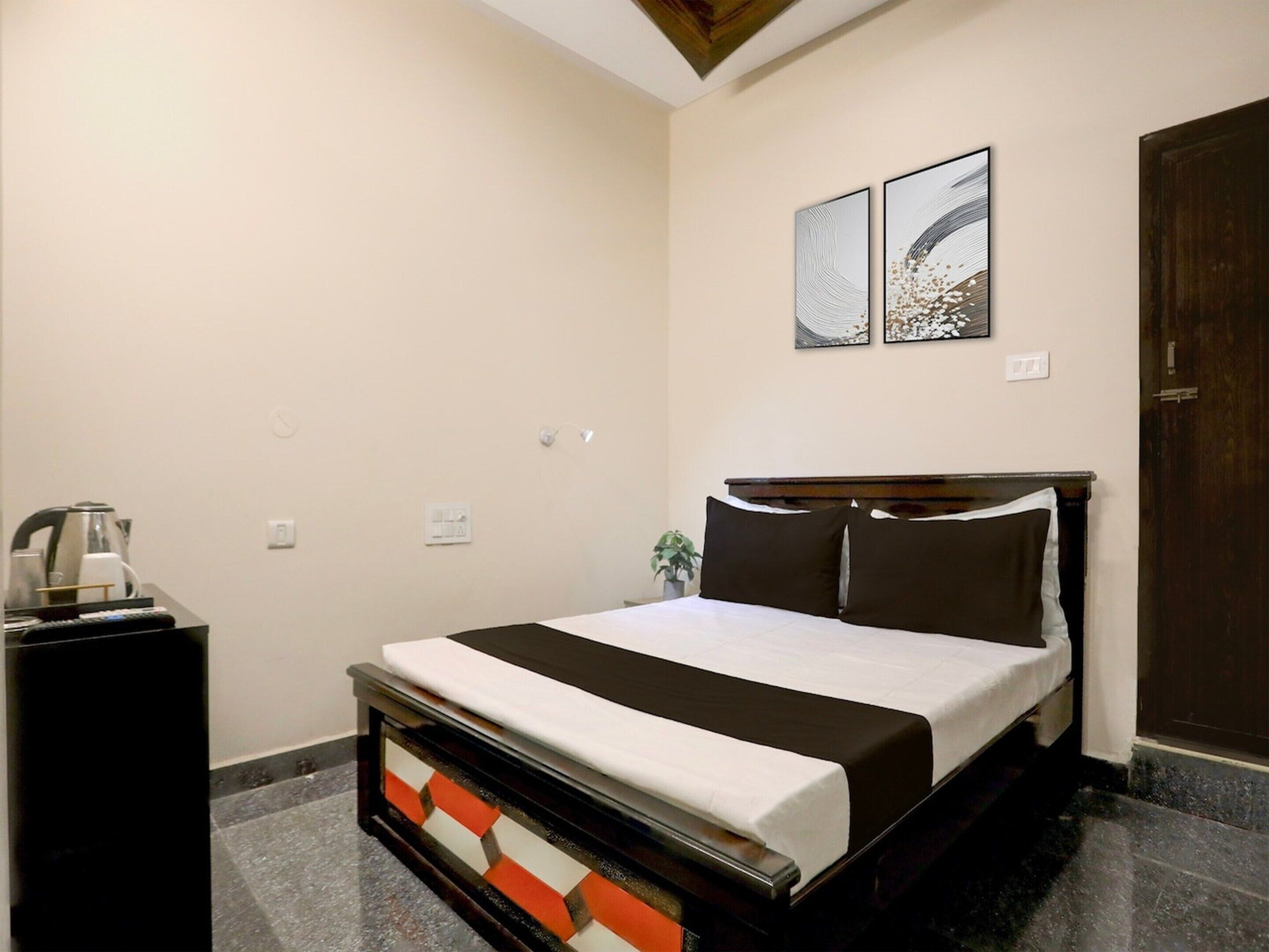 Una habitación de hotel con una cama, una mesita de noche, una obra de arte en la pared y una puerta.