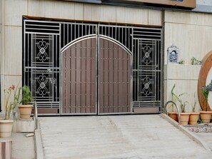 A gated entrance with a large metal gate, potted plants, and a decorative emblem on the wall.