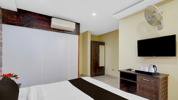 Habitación de hotel con cama, televisor, escritorio y tetera, y espejo.