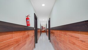 Un pasillo con paneles de madera, un extintor y una escalera al fondo.