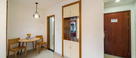 Una habitación con una mesa y sillas de madera, una lámpara colgante, un armario y una puerta con un letrero.
