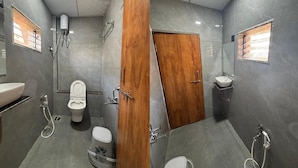A modern bathroom with a wooden door, a toilet, a bidet, a sink, and a shower. - Hotel Mojito (Vyara)