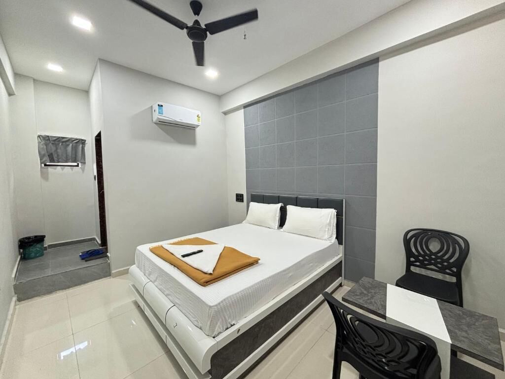 Ein Hotelzimmer mit Bett, Schreibtisch, Stuhl, Deckenventilator und Klimaanlage.