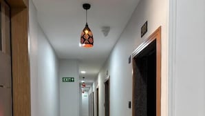 A hotel hallway with a polished floor, a directional exit sign, and a door with a dark frame. - Hotel Mojito (Vyara)