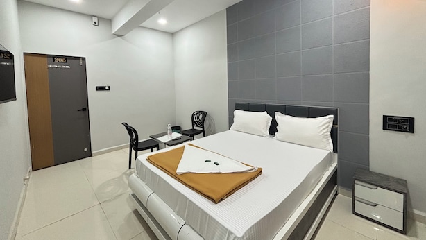 A hotel room with a bed, a desk, a chair, a ceiling fan, and a wall-mounted light. - Hotel Mojito (Vyara)
