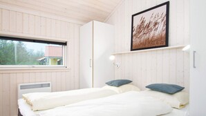 A bedroom with two beds, a window, a framed picture, and a white wardrobe. - 4 Star Holiday Home in Grossenbrode (Grossenbrode)