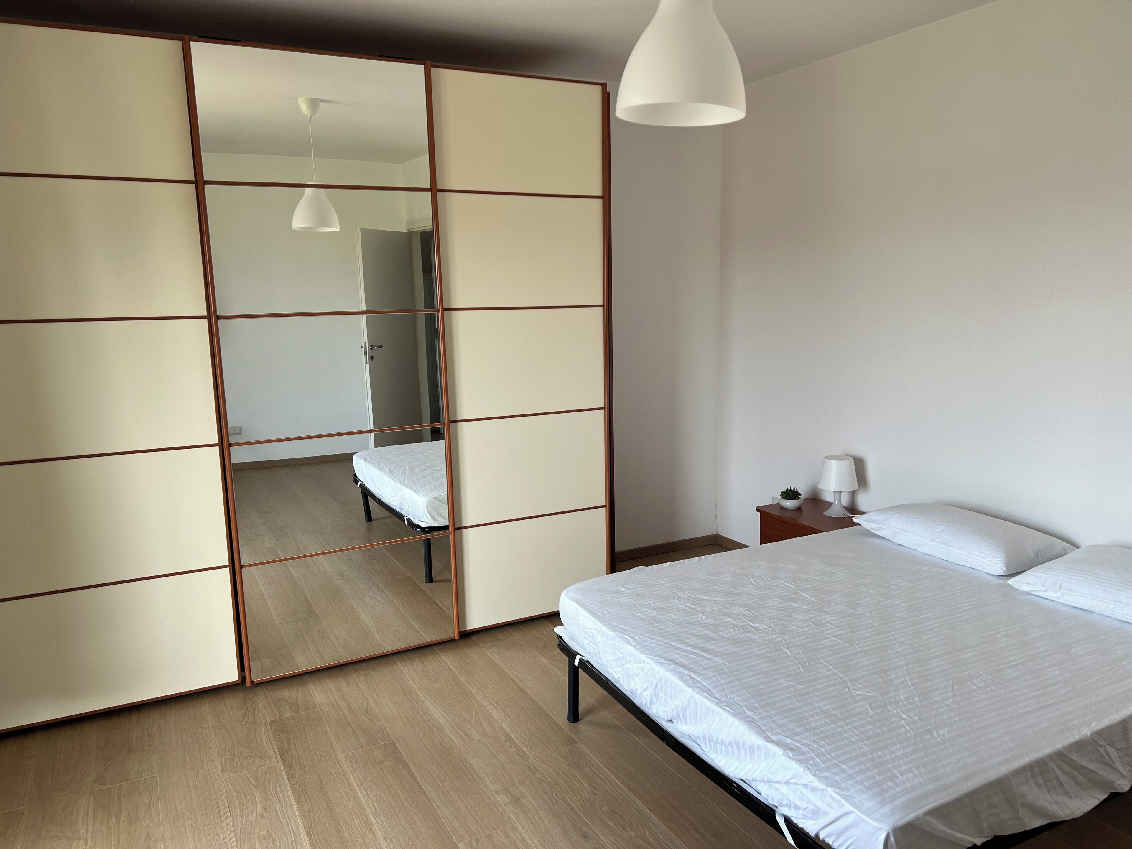 Una camera da letto con un letto, un comodino, una lampada e un armadio scorrevole.