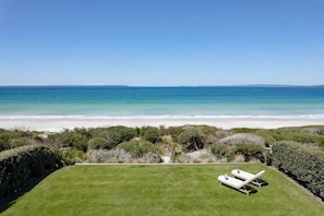 A grassy lawn with two white lounge chairs facing a beach. - 'Kindred' Absolute Beachfront Retreat (Callala Beach)