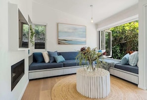 A modern living room with a curved sectional sofa, a round coffee table, and a painting on the wall. - 'Kindred' Absolute Beachfront Retreat (Callala Beach)