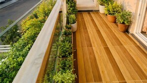 A balcony with a wooden floor, potted plants, and a view of a residential street. - Luxury 4BHK Villa Near Airport, Hyderabad Family + Work Friendly (Hyderabad)