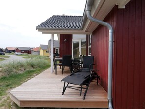 A wooden deck with outdoor furniture, a covered patio area, and a view of neighboring houses. - 4 Star Holiday Home in Grossenbrode (Grossenbrode)