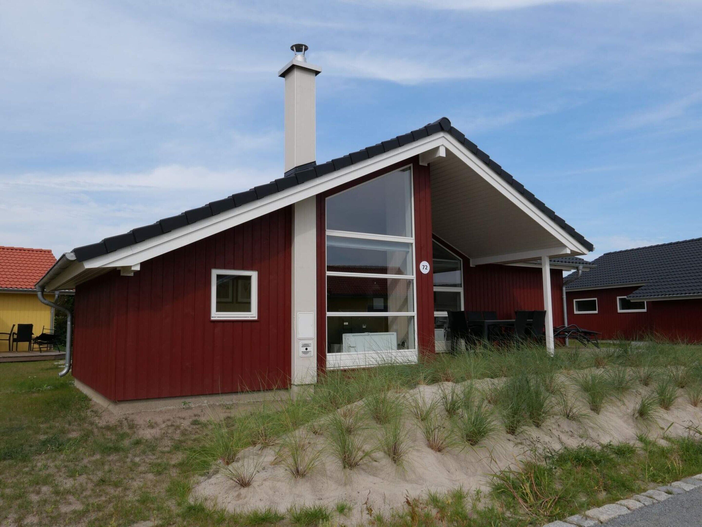 Un bâtiment rouge avec une cheminée blanche, de grandes fenêtres et un porche abrité.