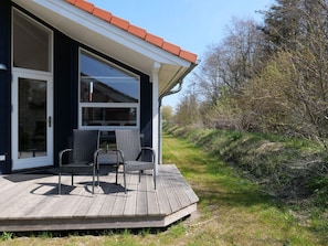 Ein modernes Haus mit einer Terrasse, zwei Stühlen und einer Glastür.