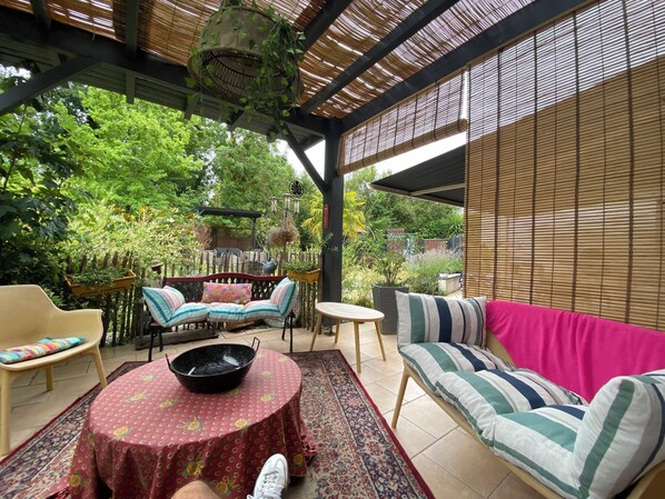 Un patio exterior con una mesa redonda, un sofá y una silla.