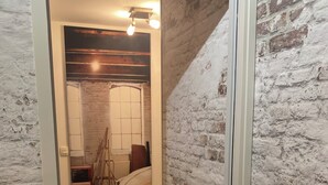 Une pièce avec un mur en briques, un lit, un radiateur et une fenêtre.