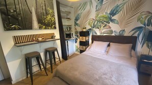 Une chambre à coucher comprenant un lit, un bureau, deux tabourets, une armoire et un miroir.