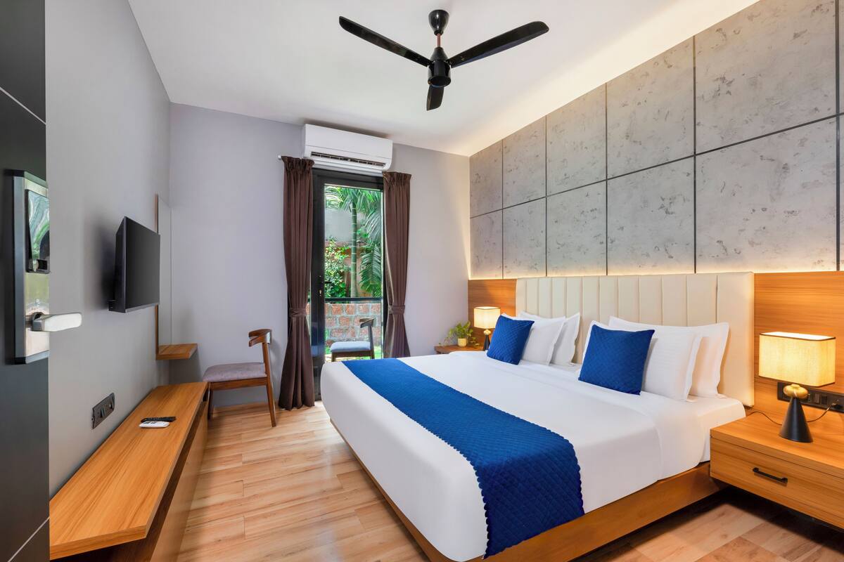 Una camera d'albergo moderna con un letto grande, una scrivania, una sedia, una TV e un condizionatore d'aria.