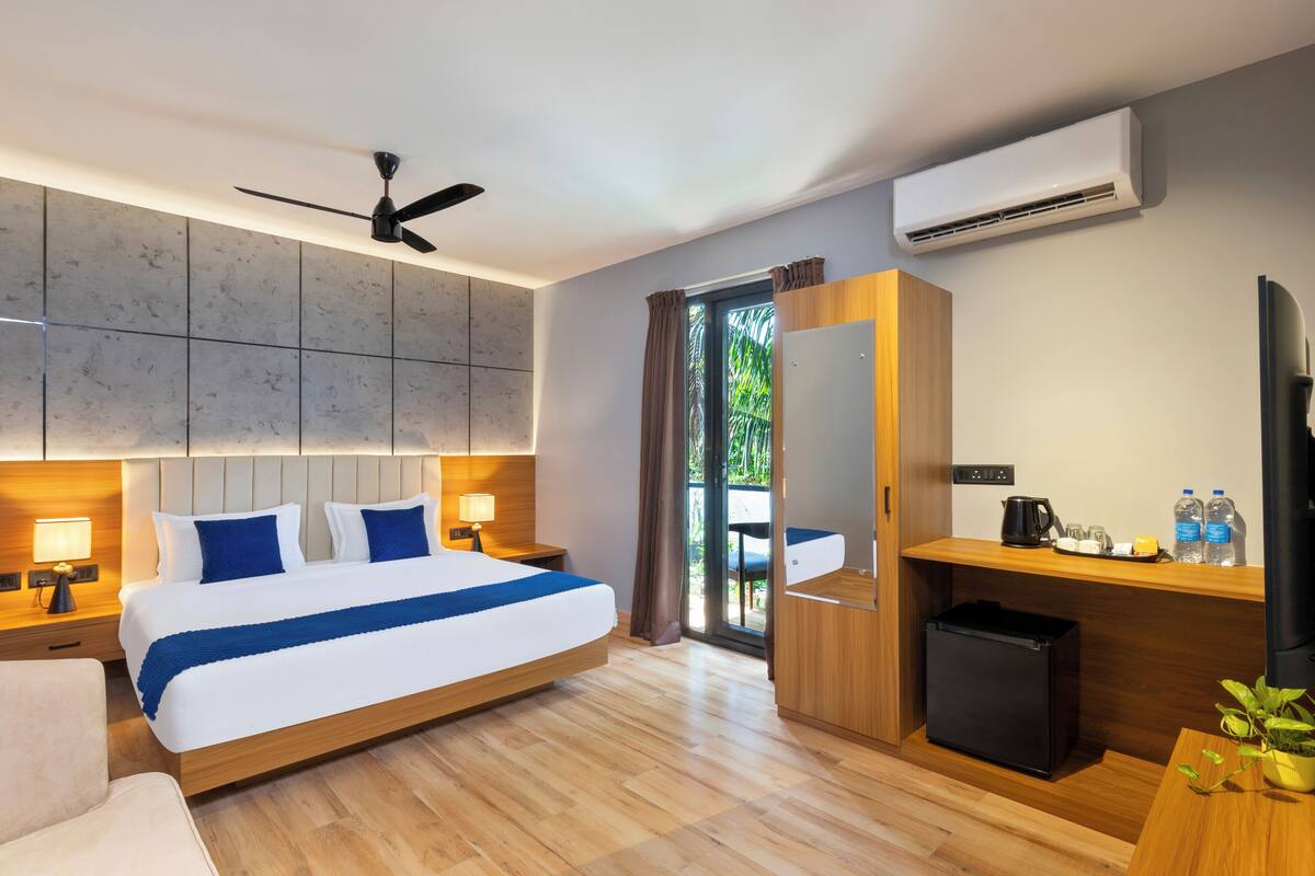 Una camera d'albergo moderna con un letto grande, una scrivania, una TV, l'aria condizionata e vista sull'esterno.