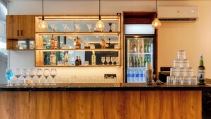 A bar area with wooden counter, hanging light fixtures, and a refrigerator stocked with bottles.
