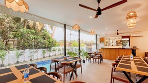 A restaurant with outdoor seating, a pool, and a bar area.
