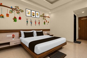 A modern hotel room with a large bed, bedside tables, a nightstand, a wall-mounted TV, and a door. - Deluxesaanvi Paradise (Bhopal)