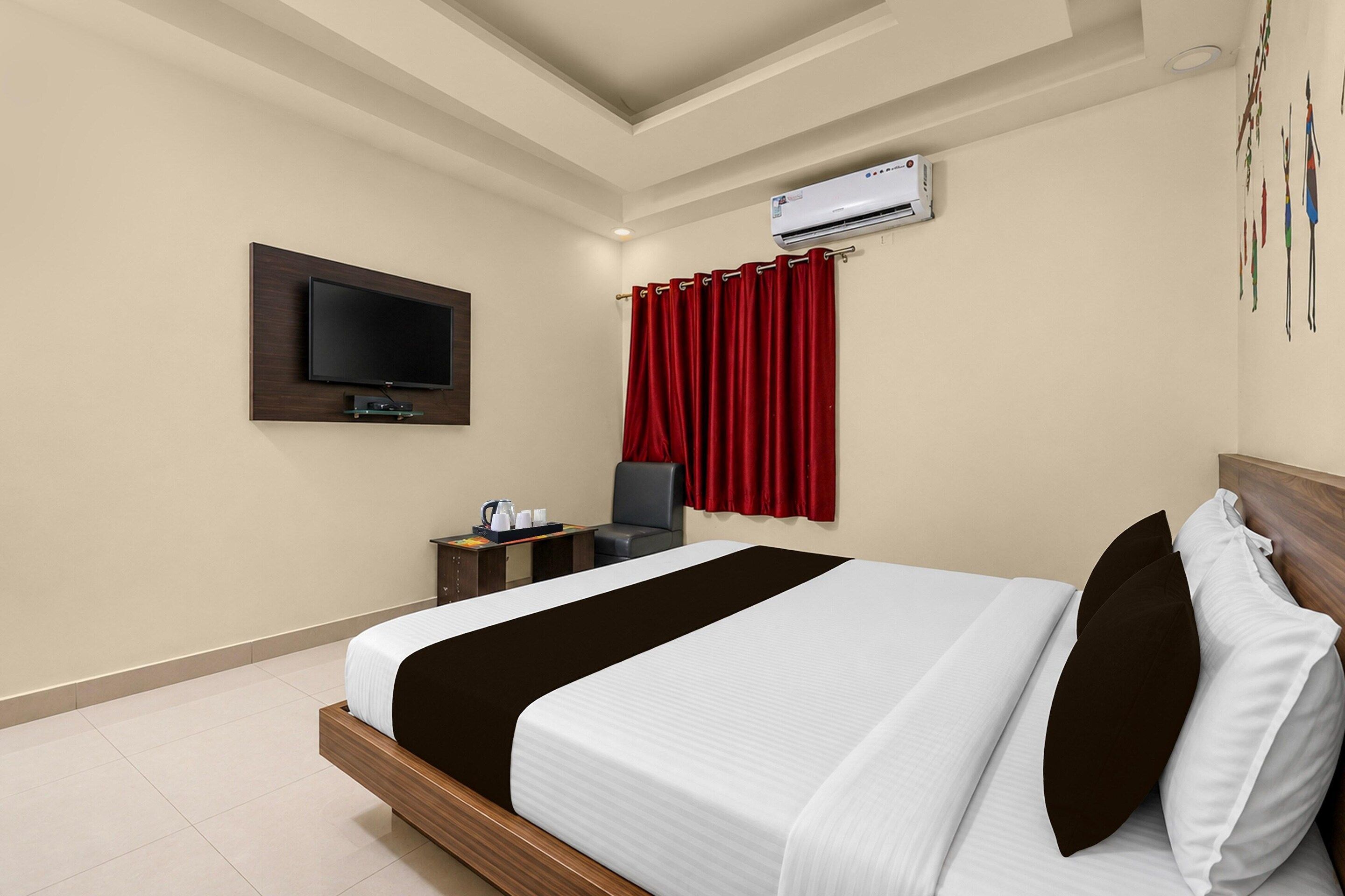 Une chambre d’hôtel équipée d’un lit, d’une télévision, d’un climatiseur et d’un bureau avec une chaise.
