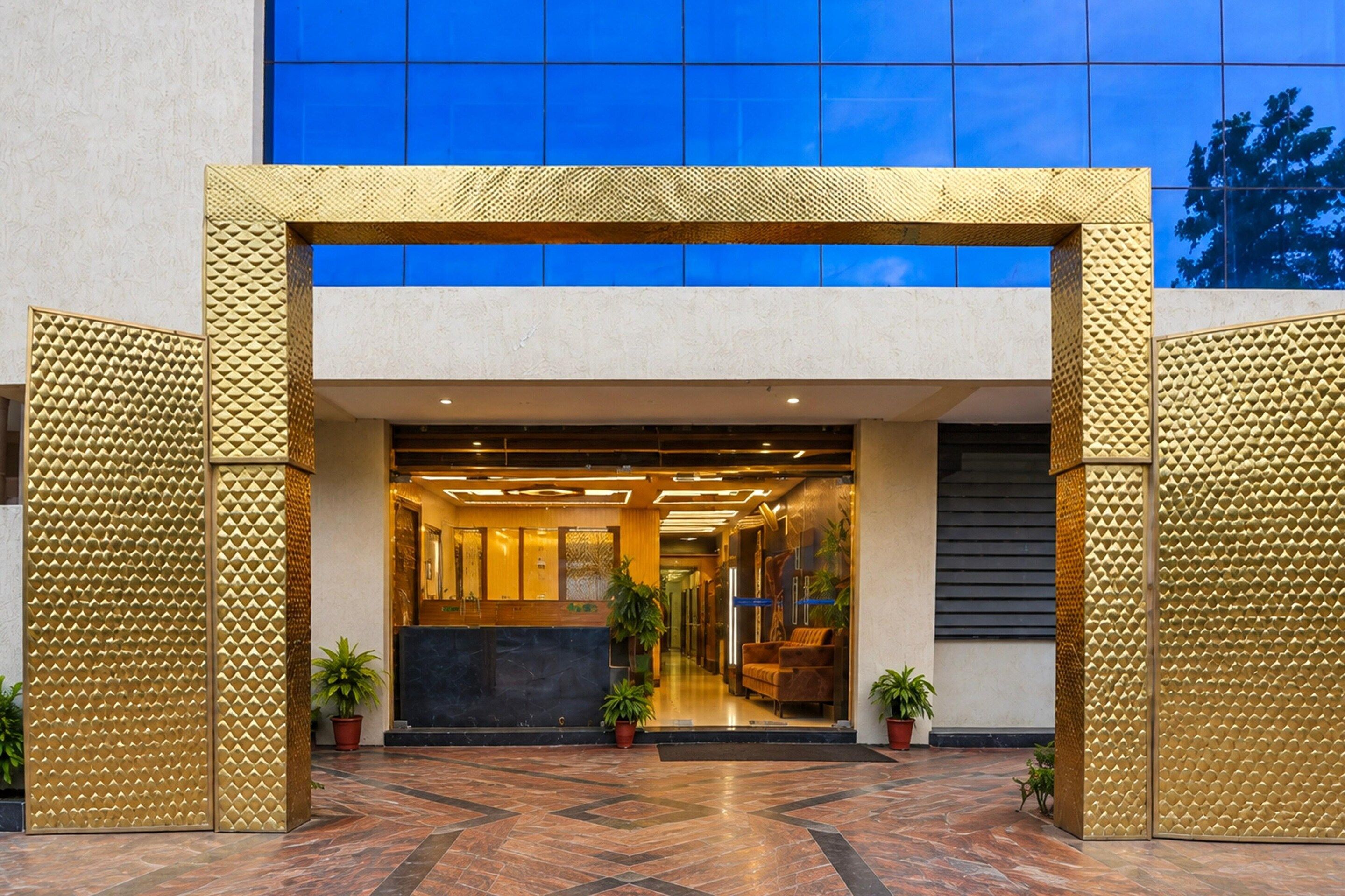 A hotel entrance with a reception desk, potted plants, and a modern design.