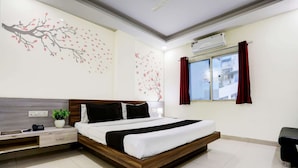 A modern hotel room with a bed, bedside table, and a window with curtains.