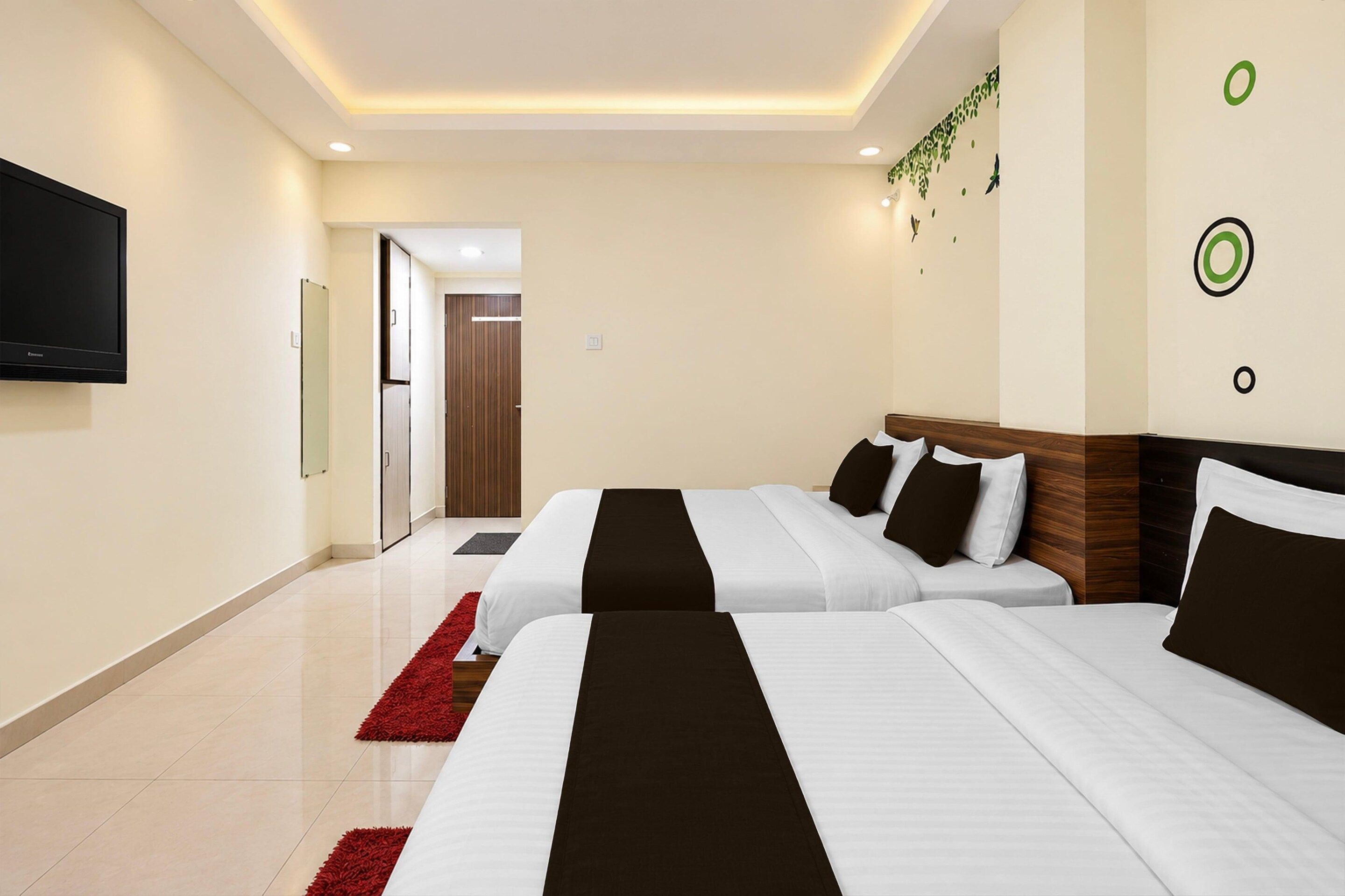 A hotel room with two beds, a TV, and a red rug.