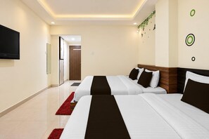 A hotel room with two beds, a TV, and a red rug. - Deluxesaanvi Paradise (Bhopal)