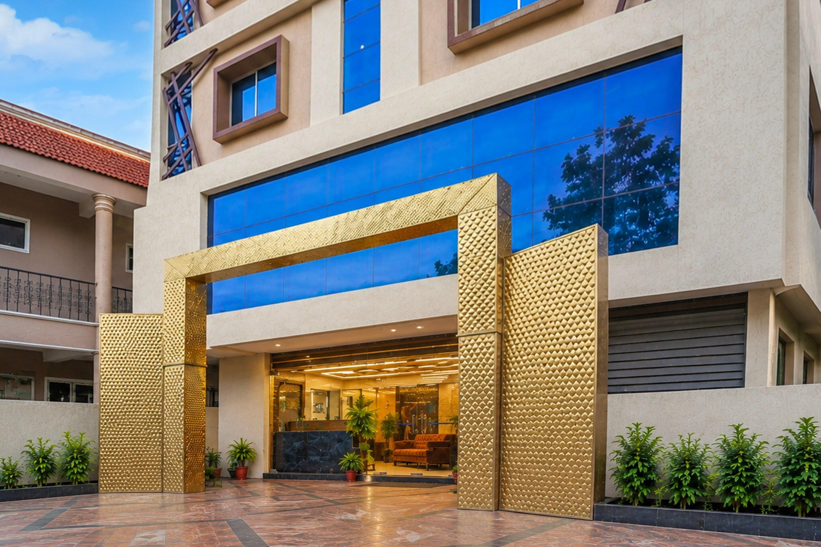 Un bâtiment moderne doté d’une grande entrée en verre et d’une structure géométrique dorée à l’avant.