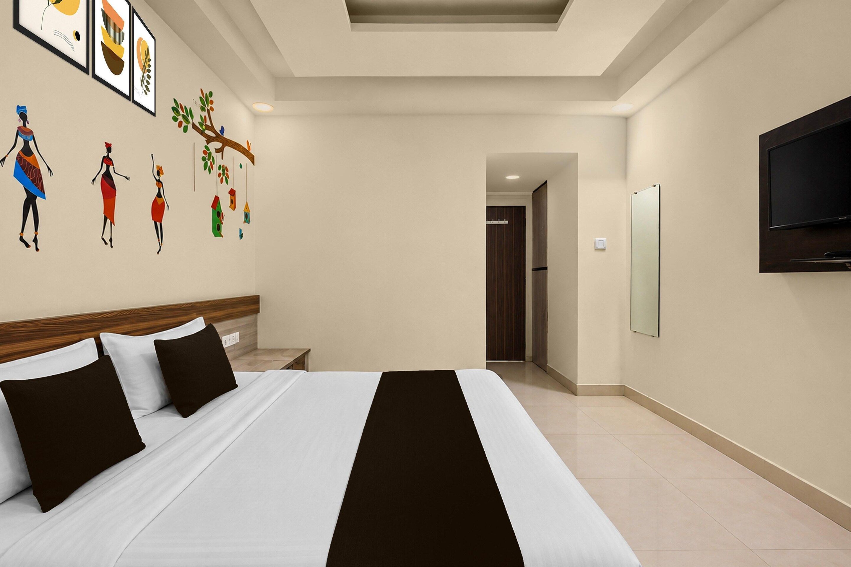 Une chambre d’hôtel avec un lit, une télévision et un mur décoré d’œuvres d’art.