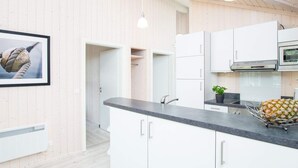 Une cuisine moderne avec des armoires blanches, un plan de travail noir et un four en acier inoxydable.