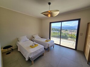 Ein Hotelzimmer mit zwei Betten, einer Deckenleuchte und einem Balkon mit Blick.