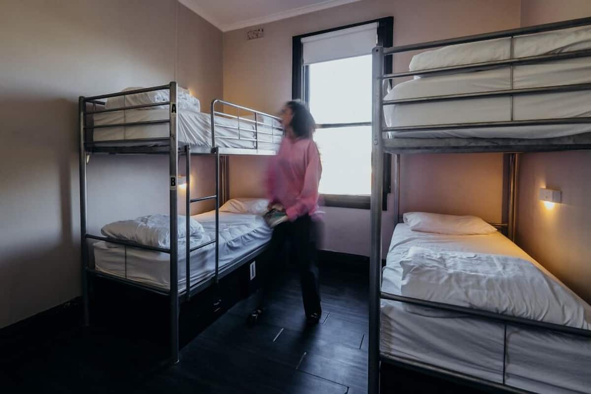 A dormitory room with bunk beds, a window, and a door.