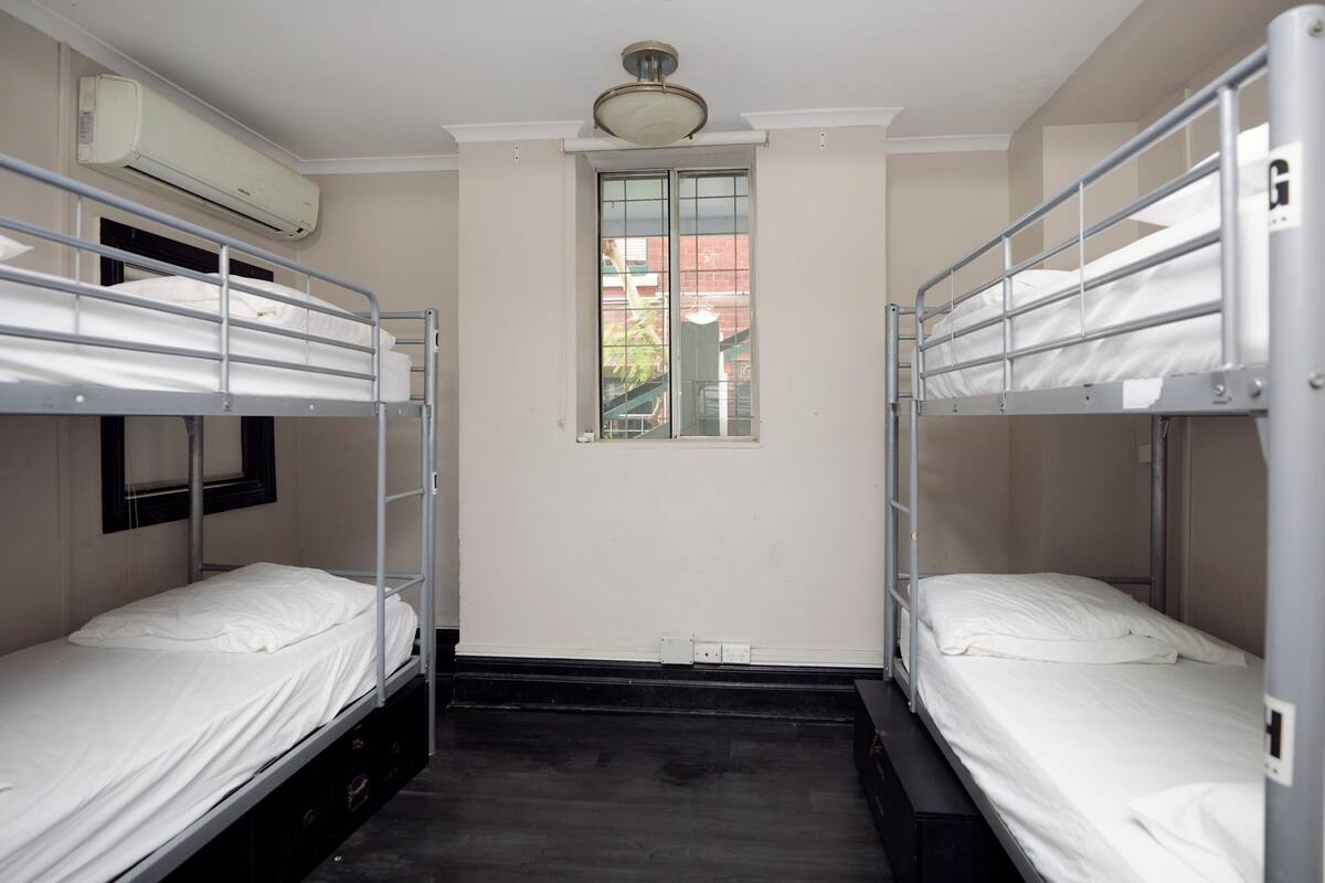 A room with bunk beds, a window, and an air conditioning unit.