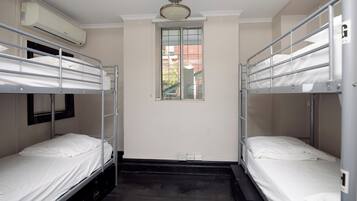 Una habitación con literas, una ventana y un equipo de aire acondicionado.